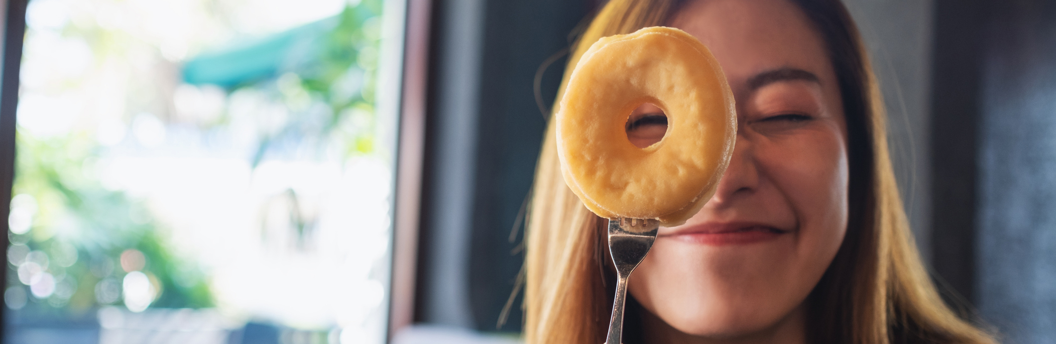 A funny young woman cover her eye and looking through donut