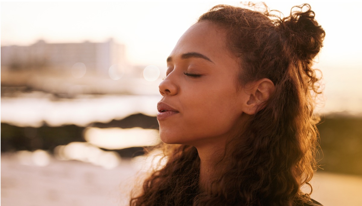 woman in a meditative pose with her eyes closed outside 