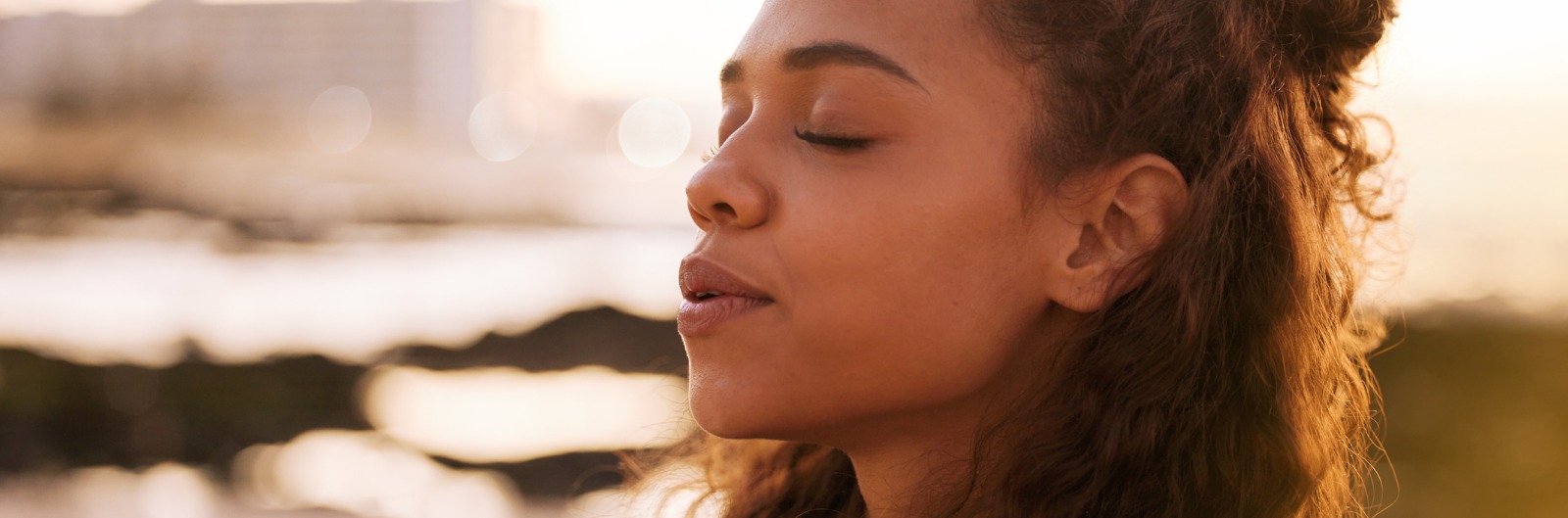 woman in a meditative pose with her eyes closed outside 