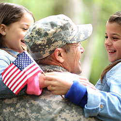 Veterans Day dad holding two young daughters one holds an American flag