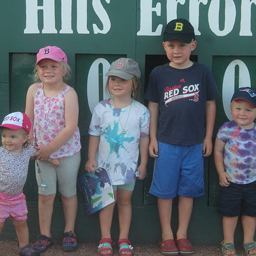 Children at Fisher Cats game in front of the scoreboard